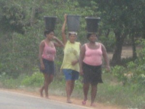 Moradoras da Vila Lobão com baldes na cabeça. (Foto/Divulgação) 